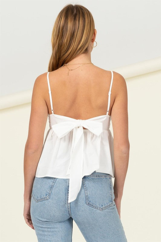 White A BABYDOLL CAMISOLE TOP SHAPES A SWEETHEART NECKLINE, SKINNY STRAPS, BUSTIER CUPS WITH PRINCESS-SEAMED ACCENTS. A SURPLICE ACCENT ON THE BODICE EXTENDS INTO A GATHERED WAIST THAT ENDS INTO A PEPLUM-INSPIRED HEM. BACK SASH ACCENT FINISHES THE LOOK!